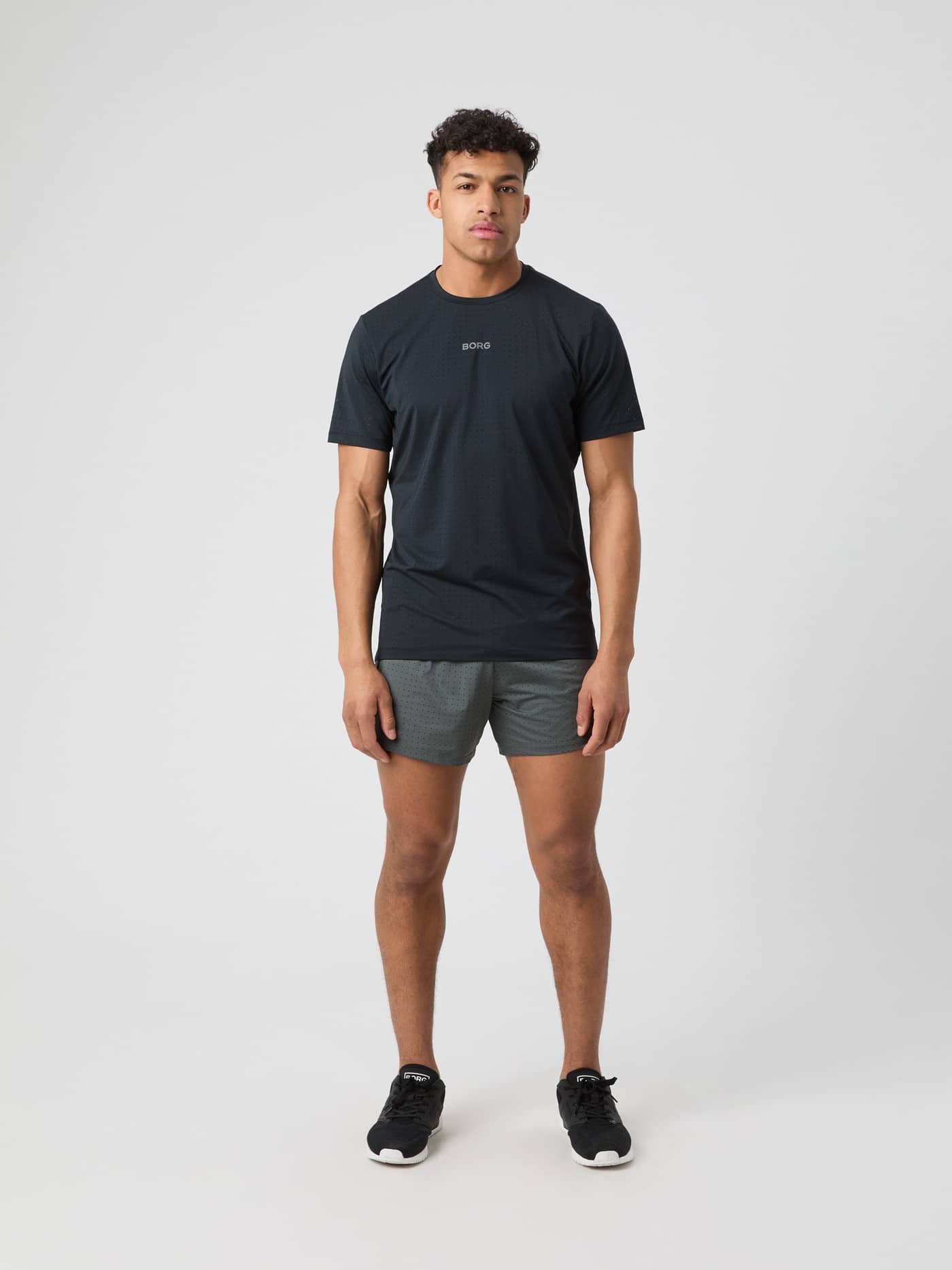 Full-body front view of a man in the Borg Performance Perforated T-Shirt in Black Beauty (Black) for running with a logo. - Image 3