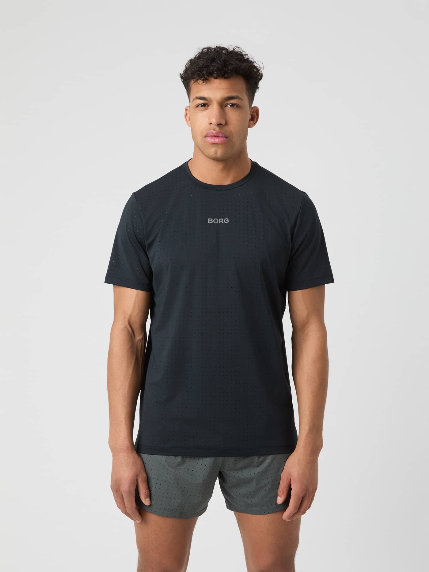Front view of a man in the Borg Performance Perforated T-Shirt in Black Beauty (Black) for running with a silver logo. - Image 1