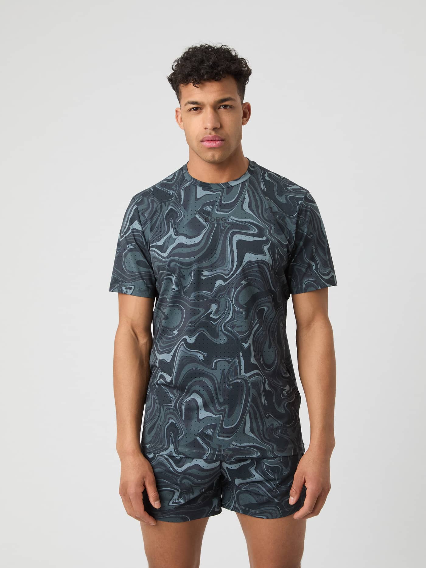 Front view of a man wearing the Borg Running Perforated T-Shirt in Liquid 1 (Grey) with a swirl pattern and black logo. - Image 1