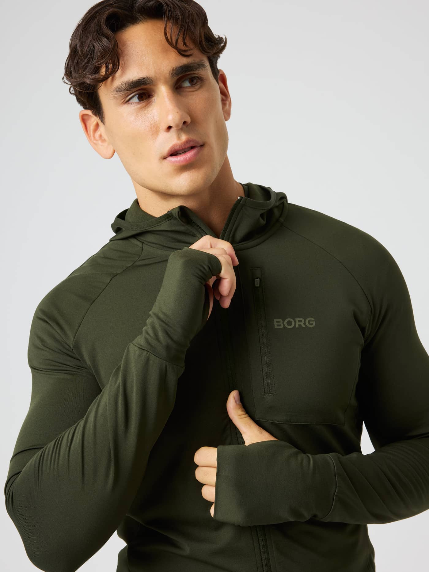 Front view of the Borg Performance Mid Layer Hood in Rosin (Green) with thumbhole sleeves and a chest pocket for running. - Image 4