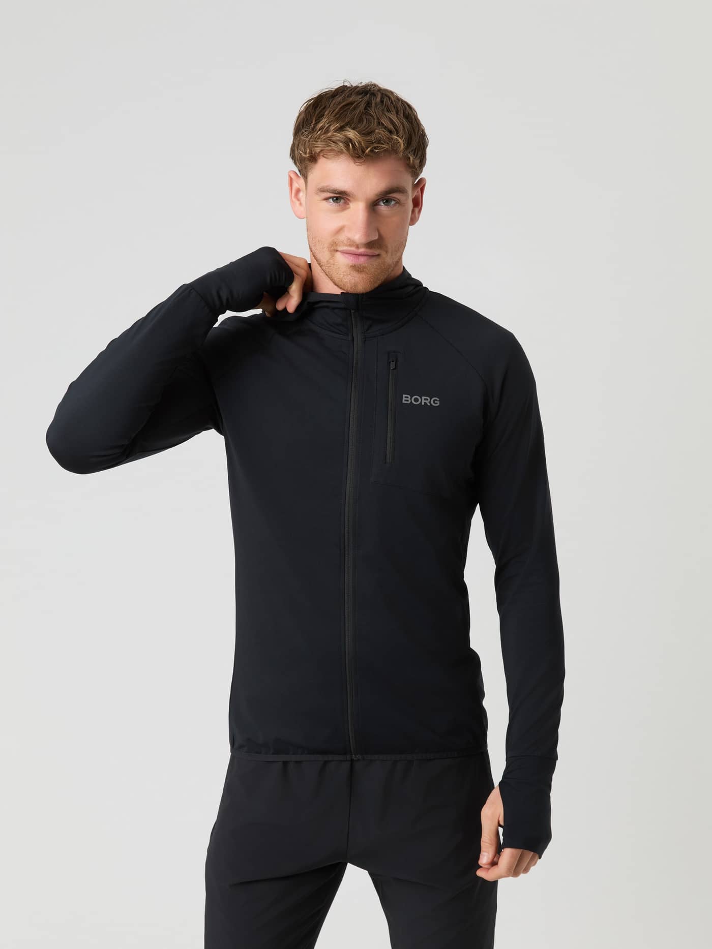 Front view of a man wearing the Borg Running Mid Layer Hood in Black Beauty (Black) with a reflective logo and thumb holes. - Image 1
