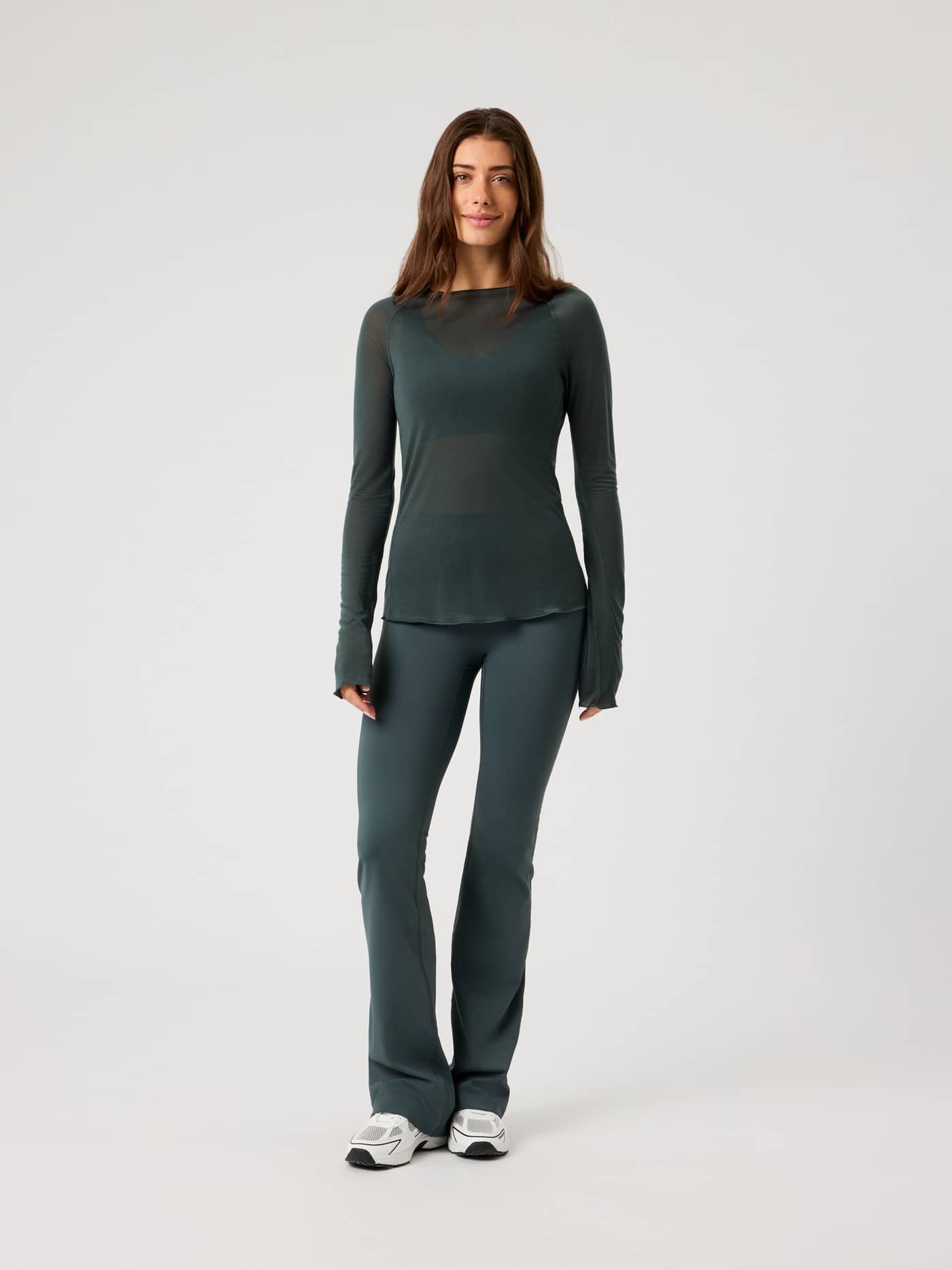 Front view of a woman in the semi-transparent Björn Borg Studio Light Long Sleeve Top in Urban Chic (Green) for training. - Image 4
