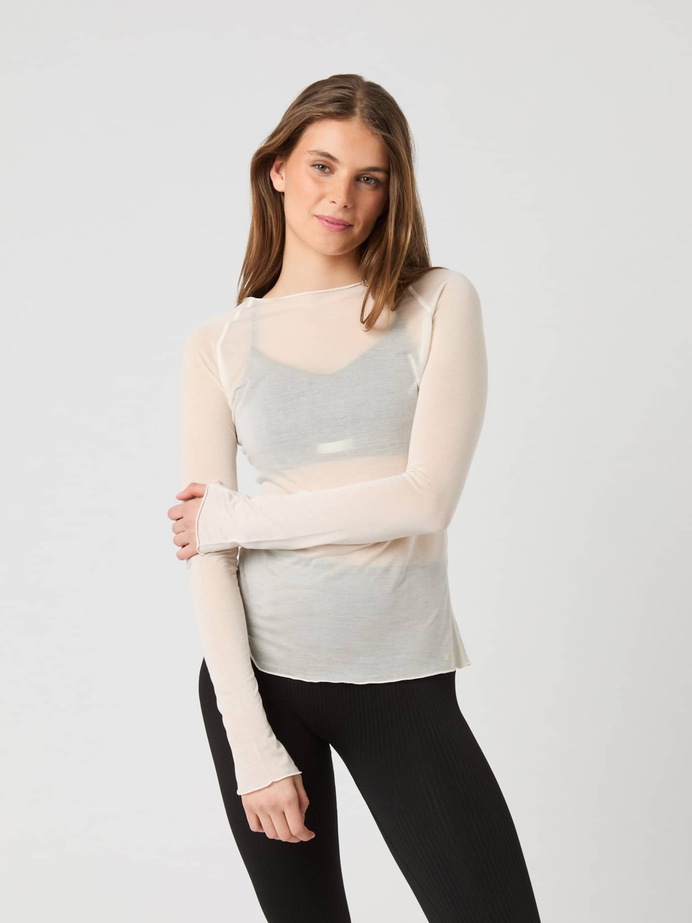 Model wearing the Björn Borg Studio Light Long Sleeve Top in birch over a black sports bra and black leggings. - Image 2