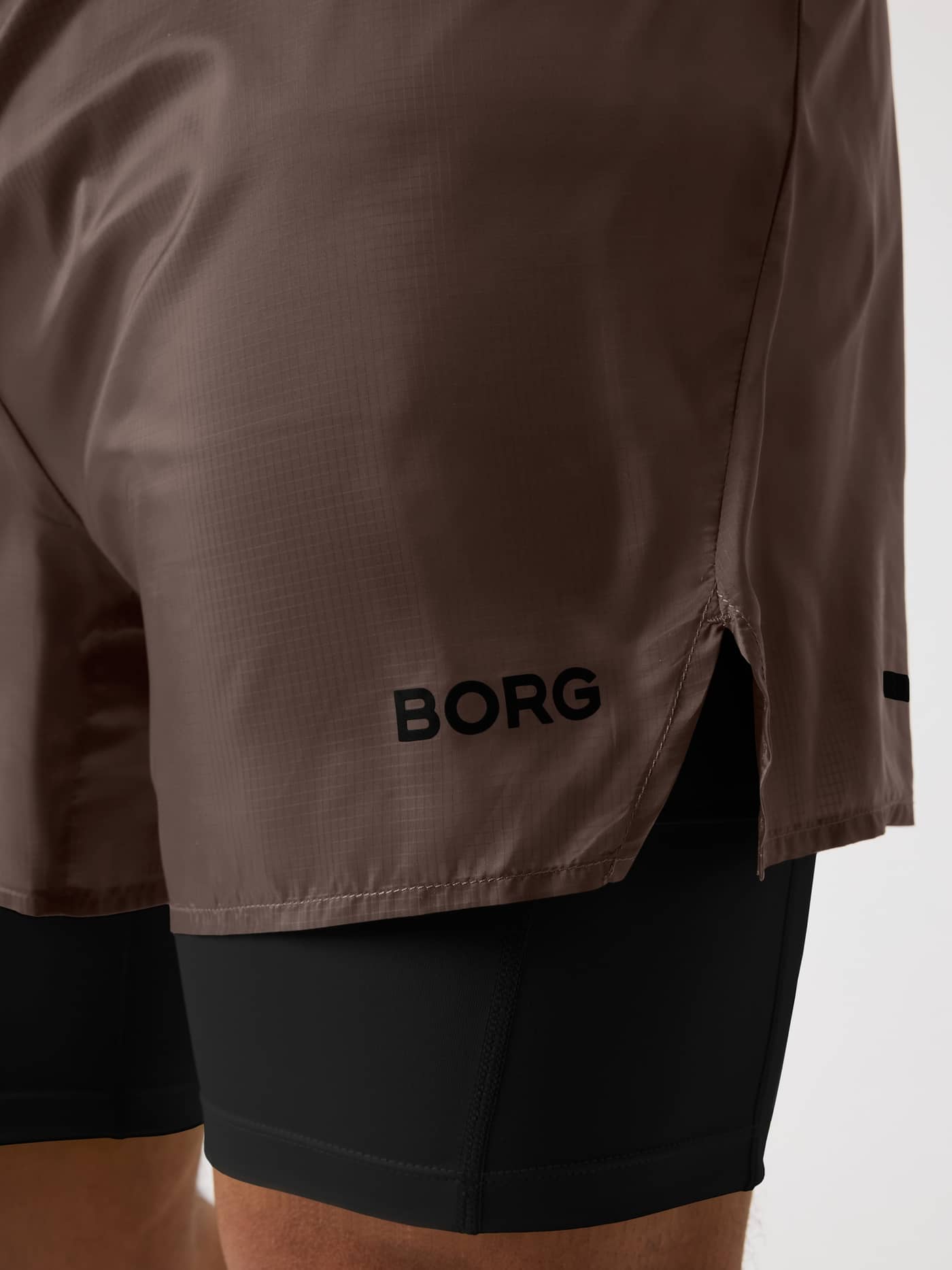 Borg Performance Shorts 2 In 1 i Falcon (Brun) i nærbillede med sort logo og sideslids til løb. - Image 6