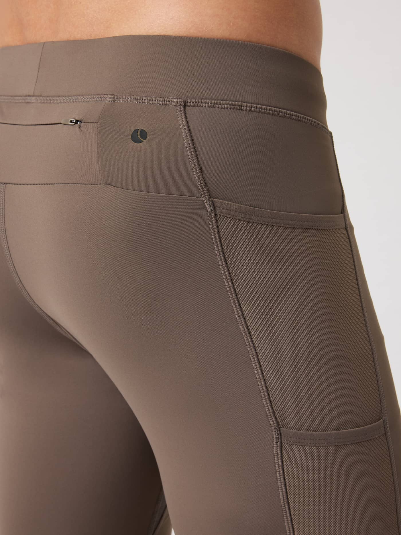 Detaljert nærbilde av Borg Running Short Tights i Falcon (Brun) med sort logo, meshlommer og glidelåslomme til løping. - Image 4
