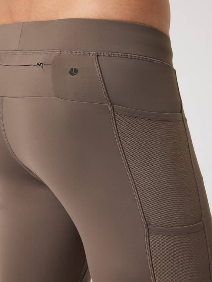 Detail van de Borg Running Short Tights in Falcon (Bruin) met mesh zijzakken, ritszak en zwart logo voor hardlopen. - Image 4