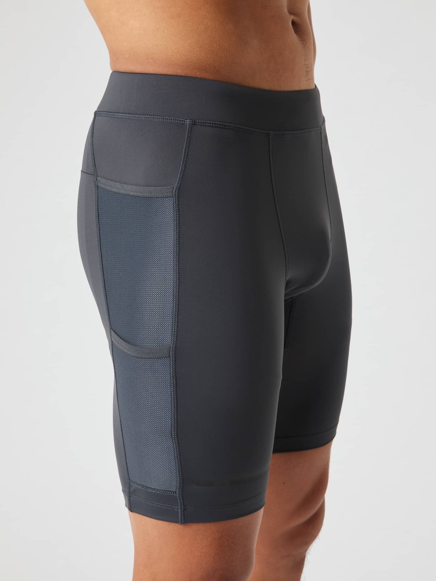 Side view of a man wearing the Borg Running Short Tights in Asphalt (Grey), featuring performance mesh side pockets. - Image 4