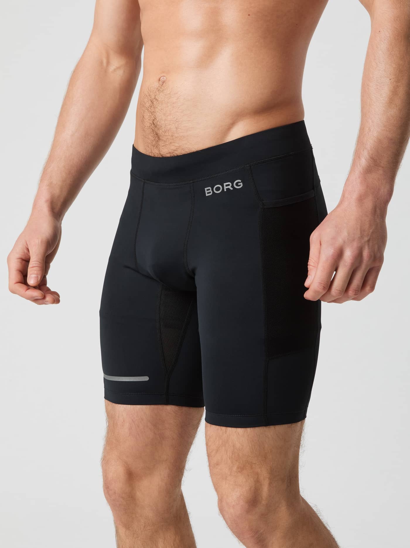 Side view of a man wearing the Borg Running Short Tights in Black Beauty (Black) with mesh pockets and a silver logo. - Image 1