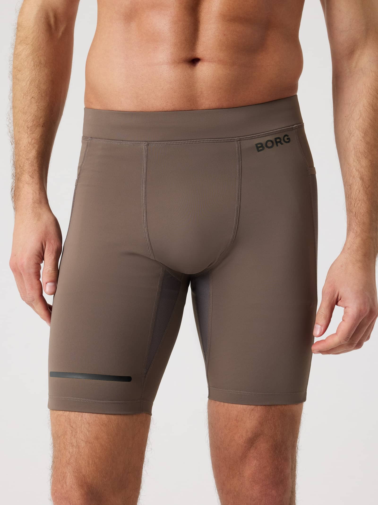 Front view of a man wearing Falcon (Brown) Borg Running Short Tights with a black logo and reflective performance strip. - Image 1