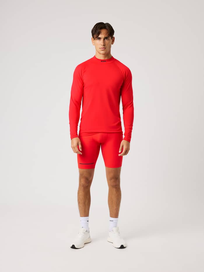 Vooraanzicht van de Borg Performance Short Tights in Flame Scarlet (Rood) voor hardlopen met zwarte logodetails.