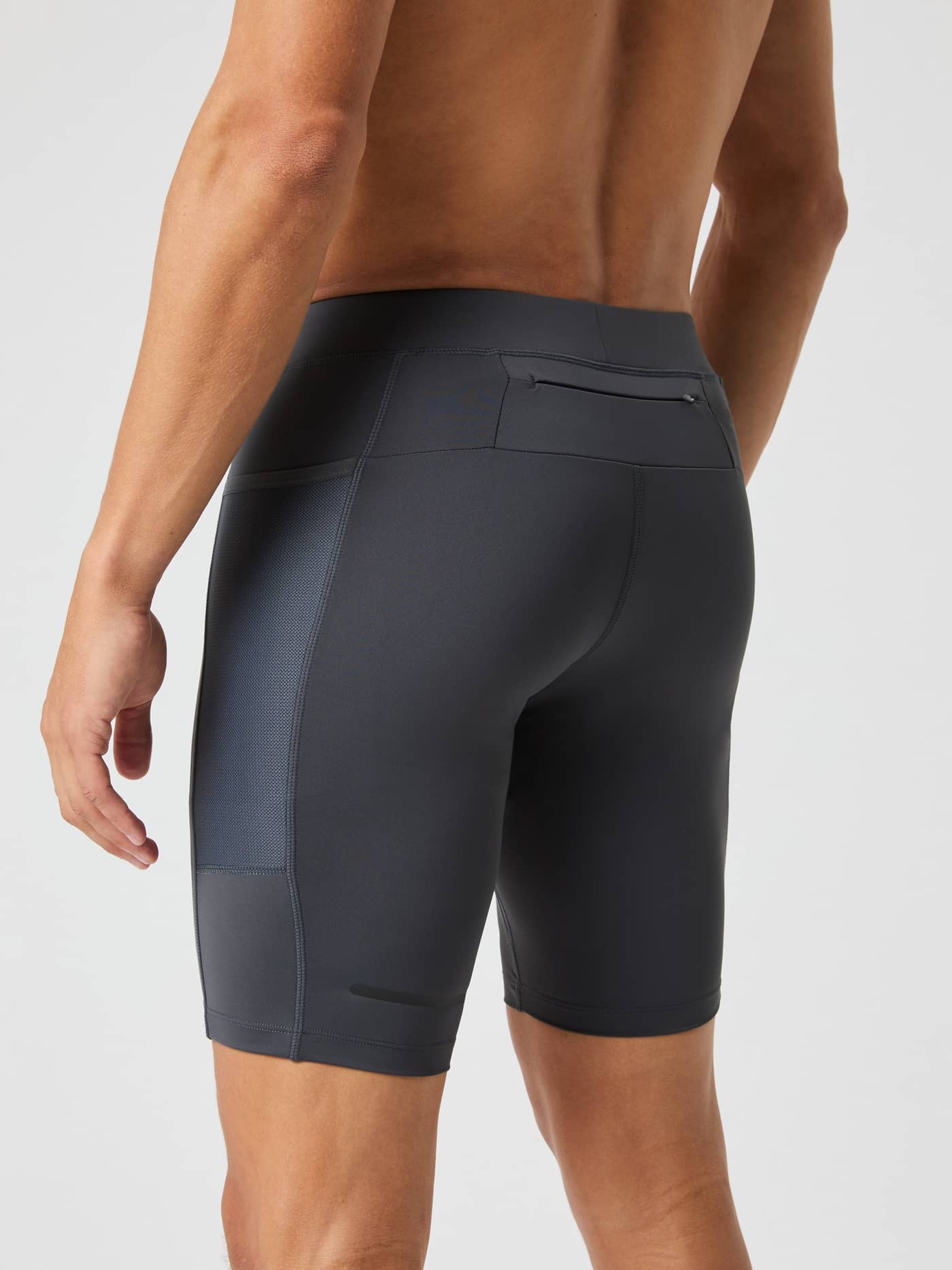 Back view of a man wearing performance Borg Running Short Tights in Asphalt (Grey), featuring mesh pockets for running. - Image 3