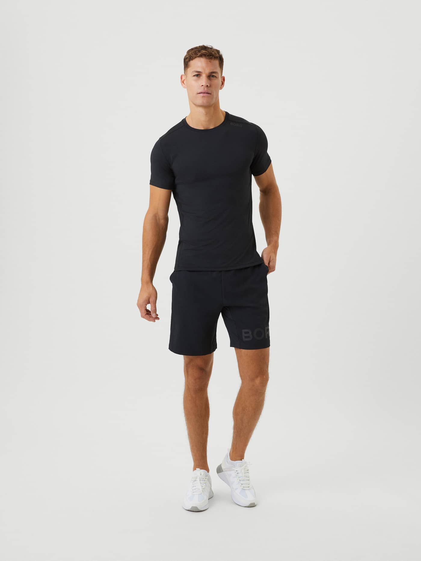 Full body view of a man wearing the black Borg 9" Shorts with a matching t-shirt and white sneakers. - Image 1