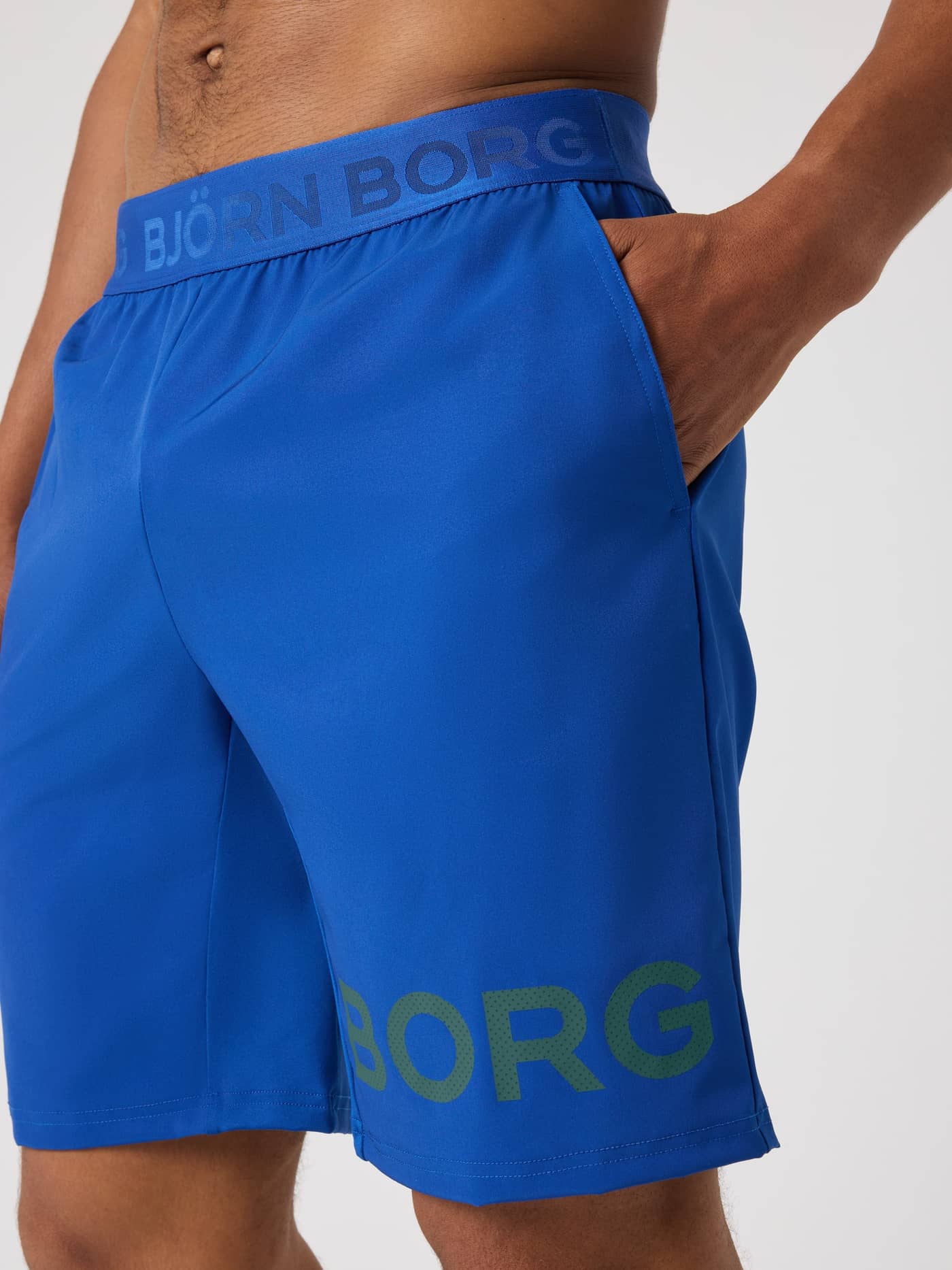 Side view of the Monaco Blue (Blue) Borg Shorts 9 Inch for training and tennis, with a pocket and grey perforated logo. - Image 4