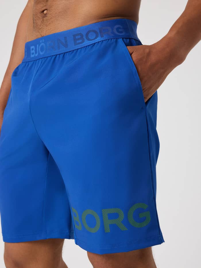 Borg Shorts 9 Inch i Monaco Blue (Blå) set fra siden med lomme og gråt perforeret logo til tennis og træning. - Image 4