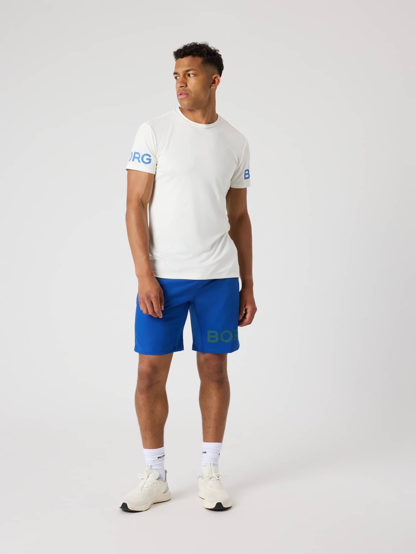 Full-body front view of a man wearing the Monaco Blue (Blue) Borg Shorts 9 Inch with a perforated logo for training. - Image 3