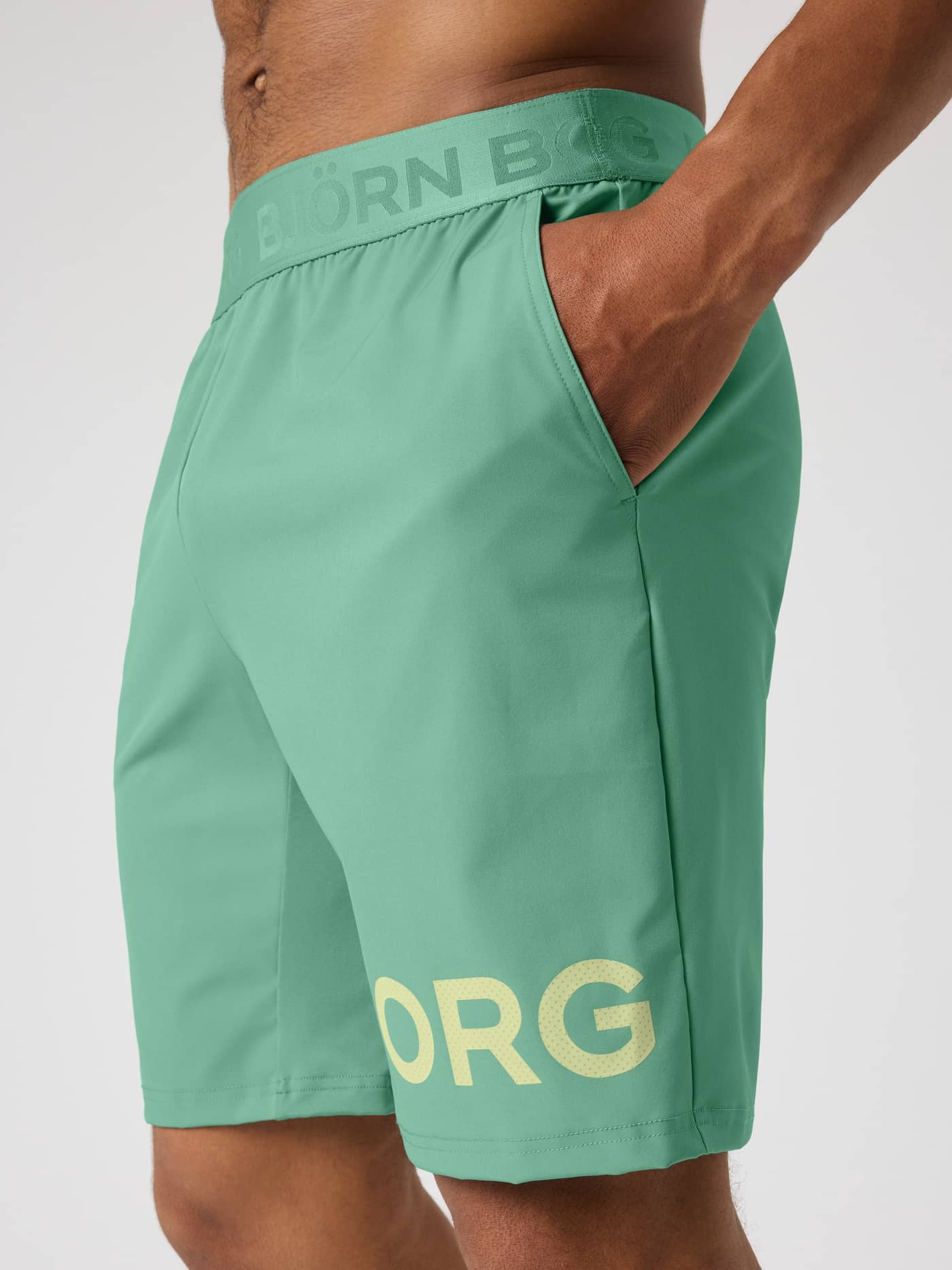 Borg Shorts 9 Inch i Malachite Green (Grøn) set fra siden til træning med forstærket skridt og lysegult logo. - Image 4
