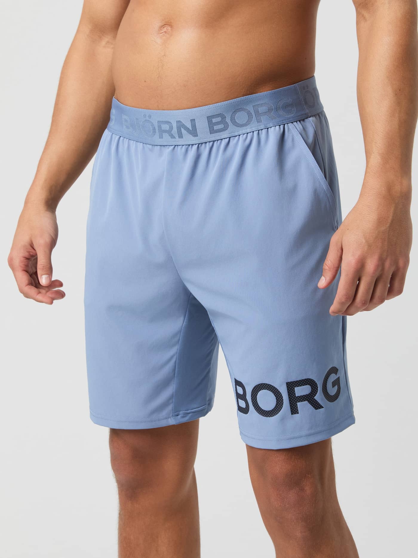 Front view of a man wearing the light blue Björn Borg 9" Shorts with a large BORG logo on the leg. - Image 1