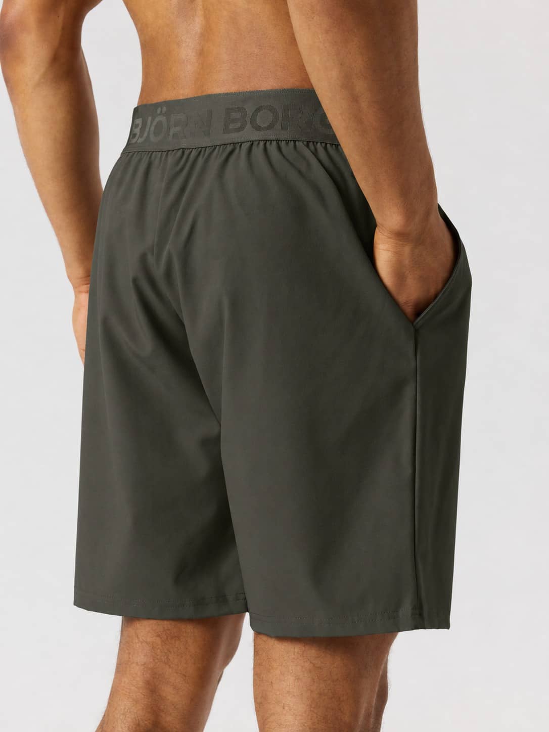 Back view of a model wearing the Borg Shorts 9 Inch in Rosin (Green) for training, with a branded waistband and pockets. - Image 2