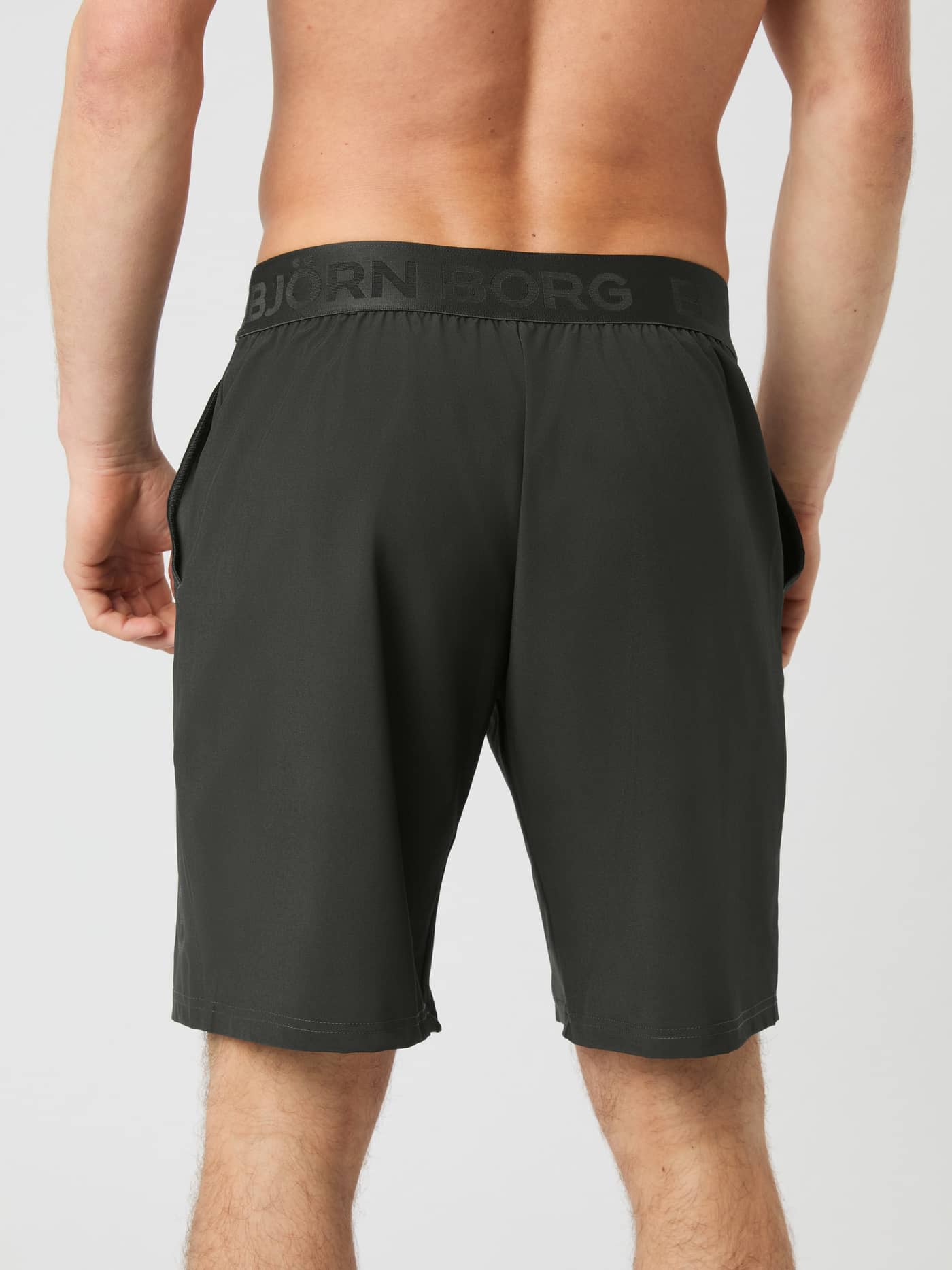 Back view of a man wearing the dark green Björn Borg Borg 9-inch Shorts, showing the elastic logo waistband and fit. - Image 2