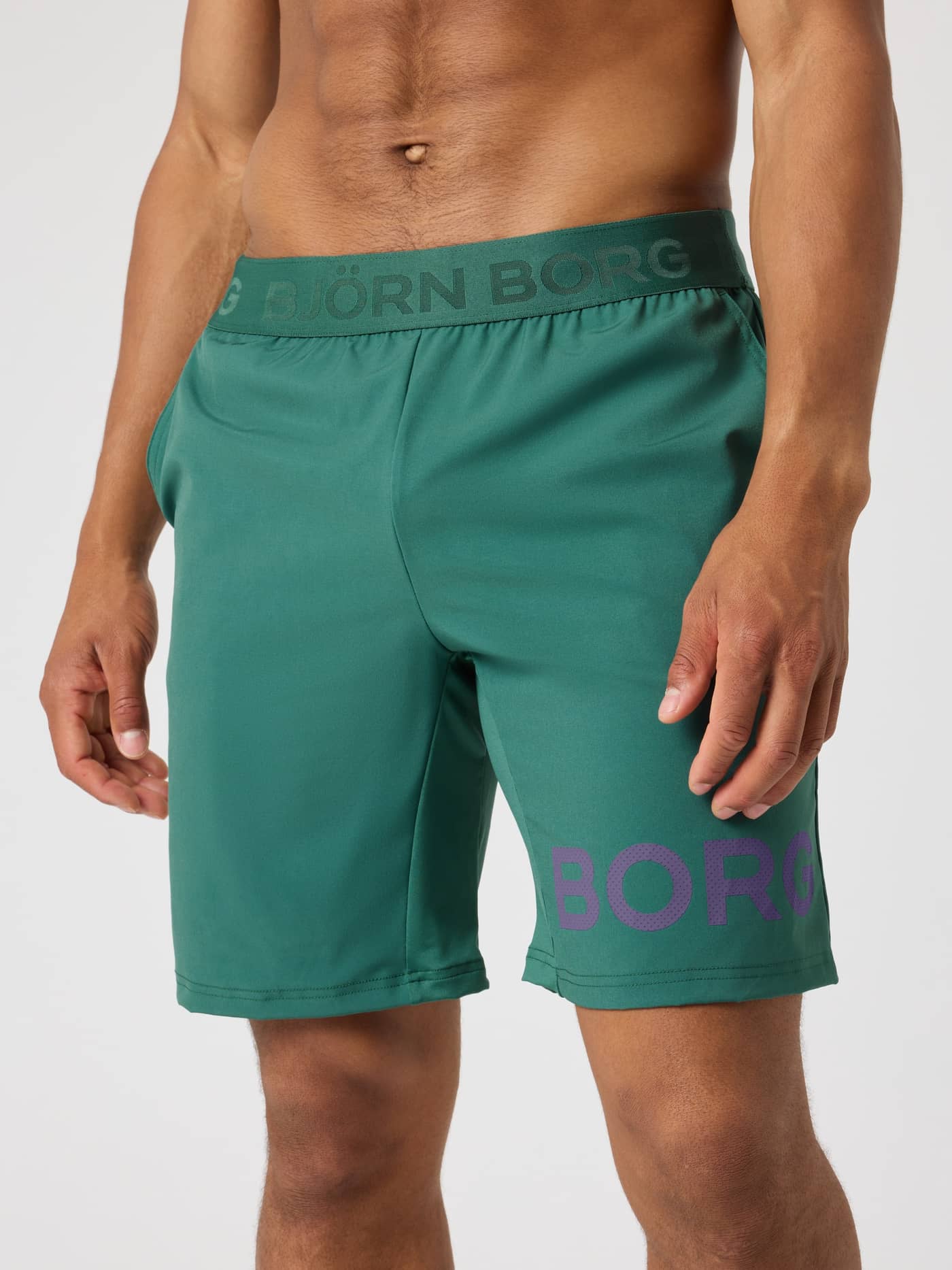 Front view of a model wearing the Borg Shorts 9 Inch in Mallard Green (Green) with a purple perforated logo for training. - Image 1