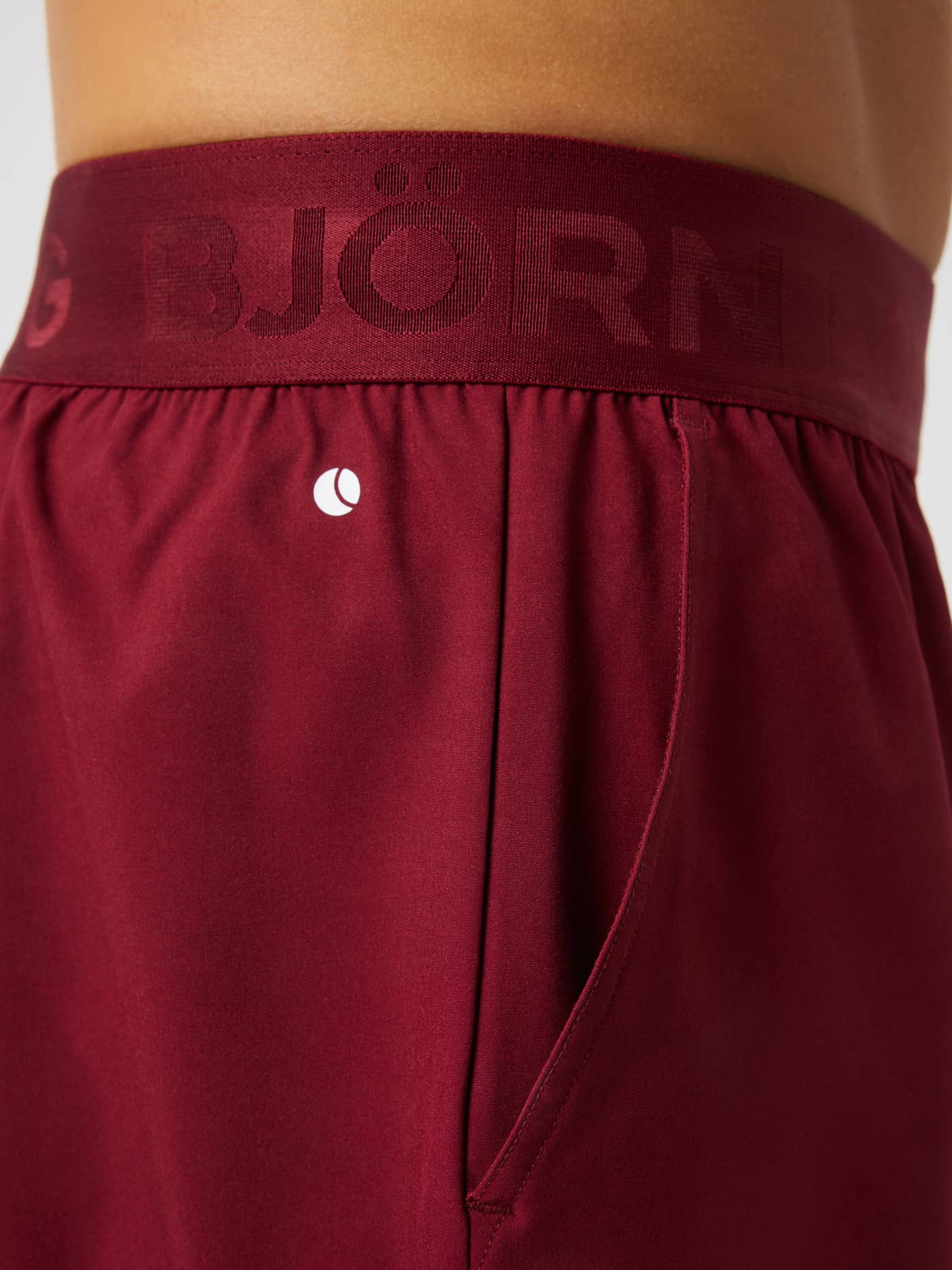 Close-up of the Borg Shorts 9 Inch in cabernet (red) highlighting the elastic logo waistband and side pocket for training. - Image 5