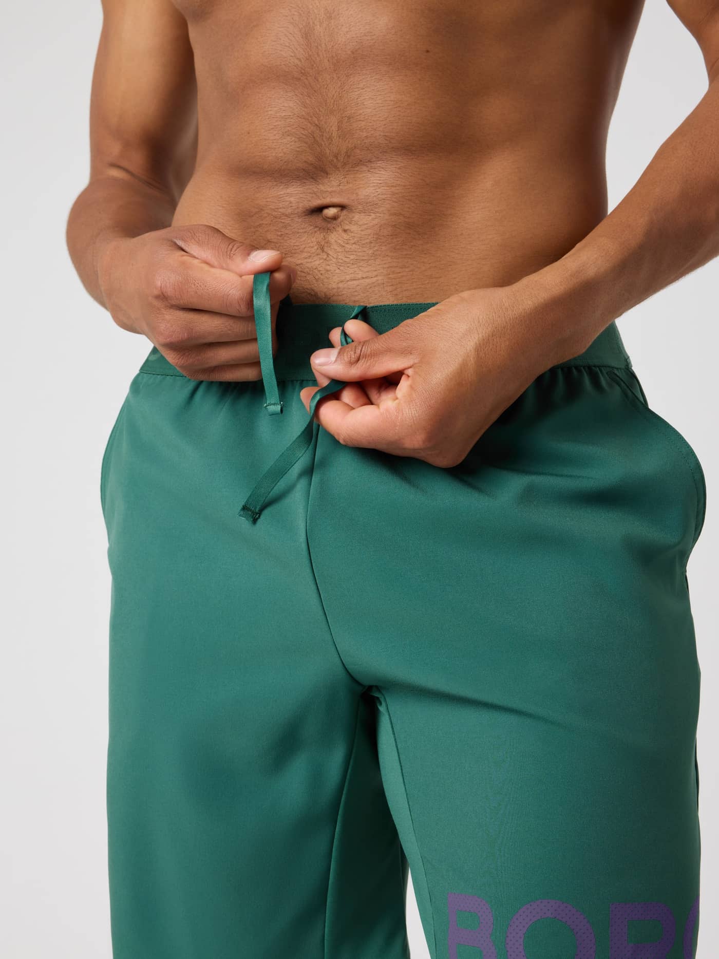 Gros plan d'un homme ajustant le cordon de serrage du Borg Shorts 9 Inch en Mallard Green (Vert) pour l'entraînement. - Image 5