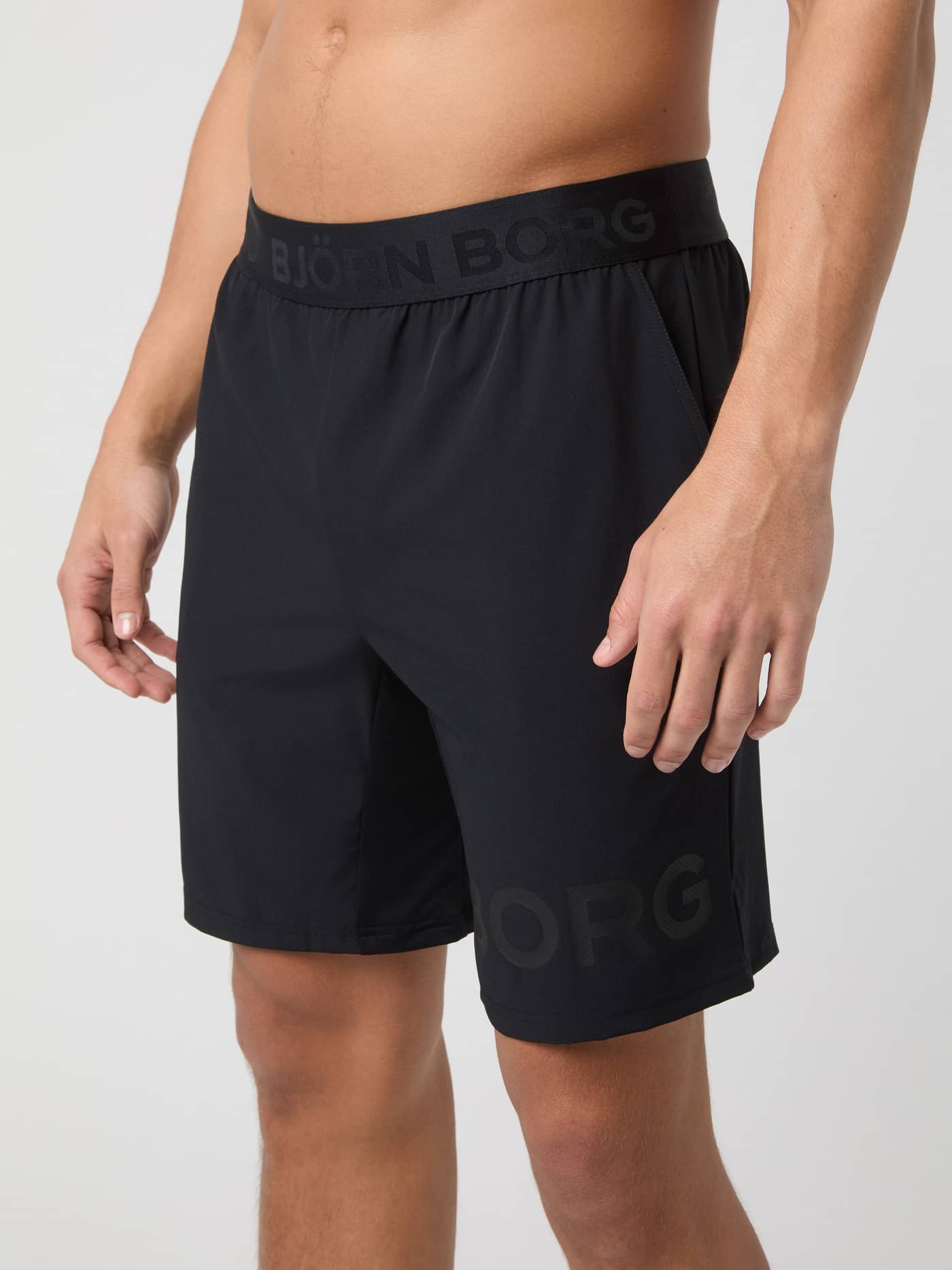 Borg Shorts 9 Inch i Black Tonal Logo (Svart) sedda från sidan på en man, perfekta för träning och tennis. - Image 2