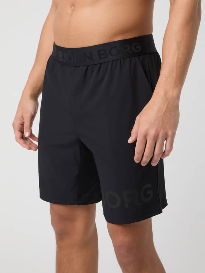 Vue de profil d'un homme en Borg Shorts 9 Inch Black Tonal Logo (Noir) au logo noir, idéal pour le tennis et l'entraînement. - Image 2