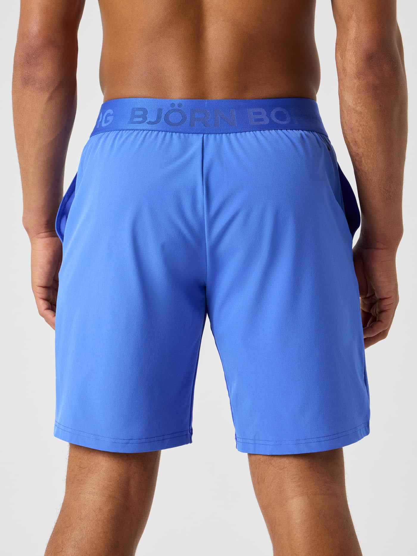 Back view of a man wearing Björn Borg Shorts 9 Inch in Amparo Blue (Blue) with a blue logo waistband for training. - Image 2