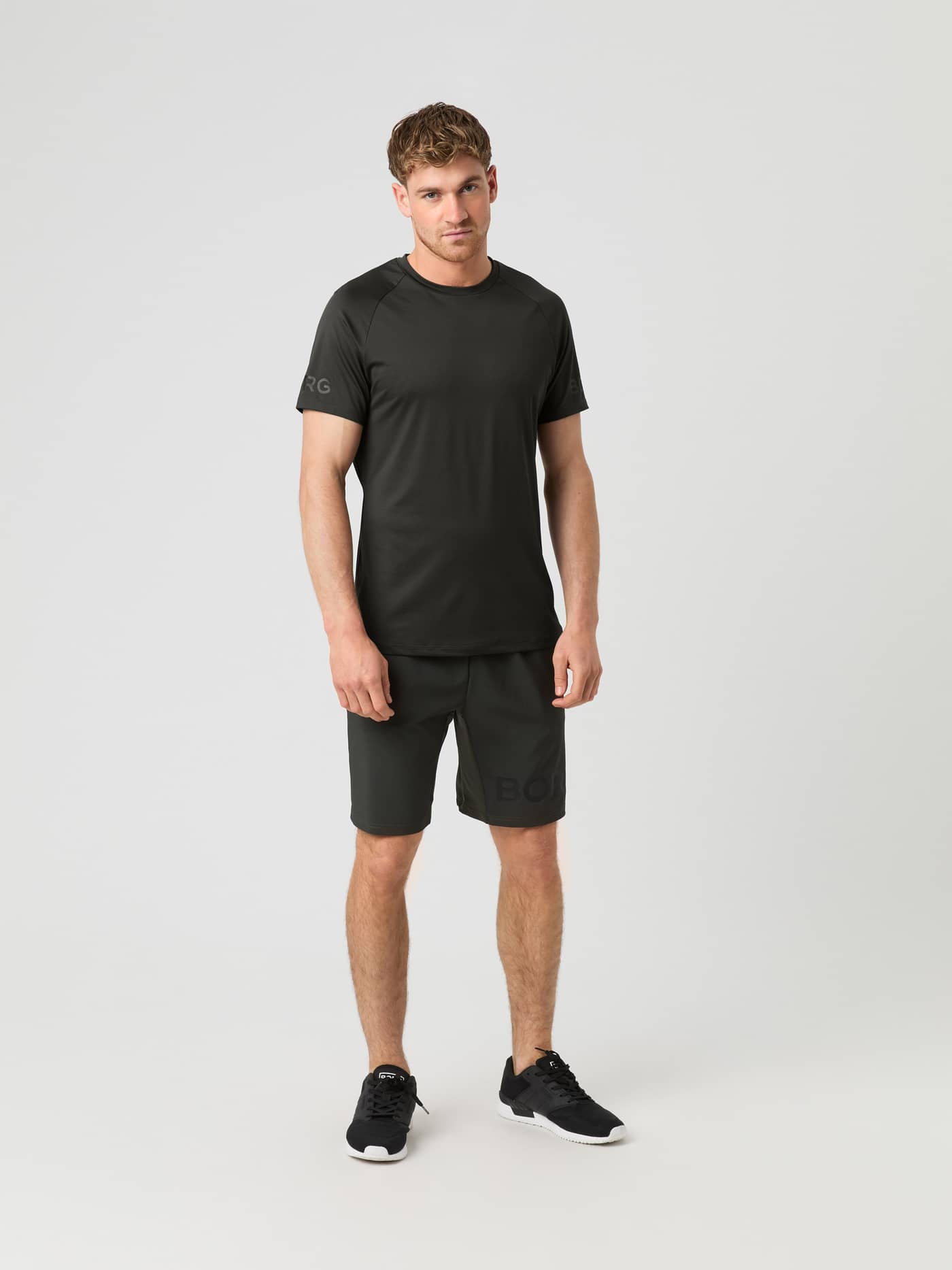 Full front view of a model wearing the Björn Borg 9" Shorts in peat, styled with a matching t-shirt and black trainers. - Image 3