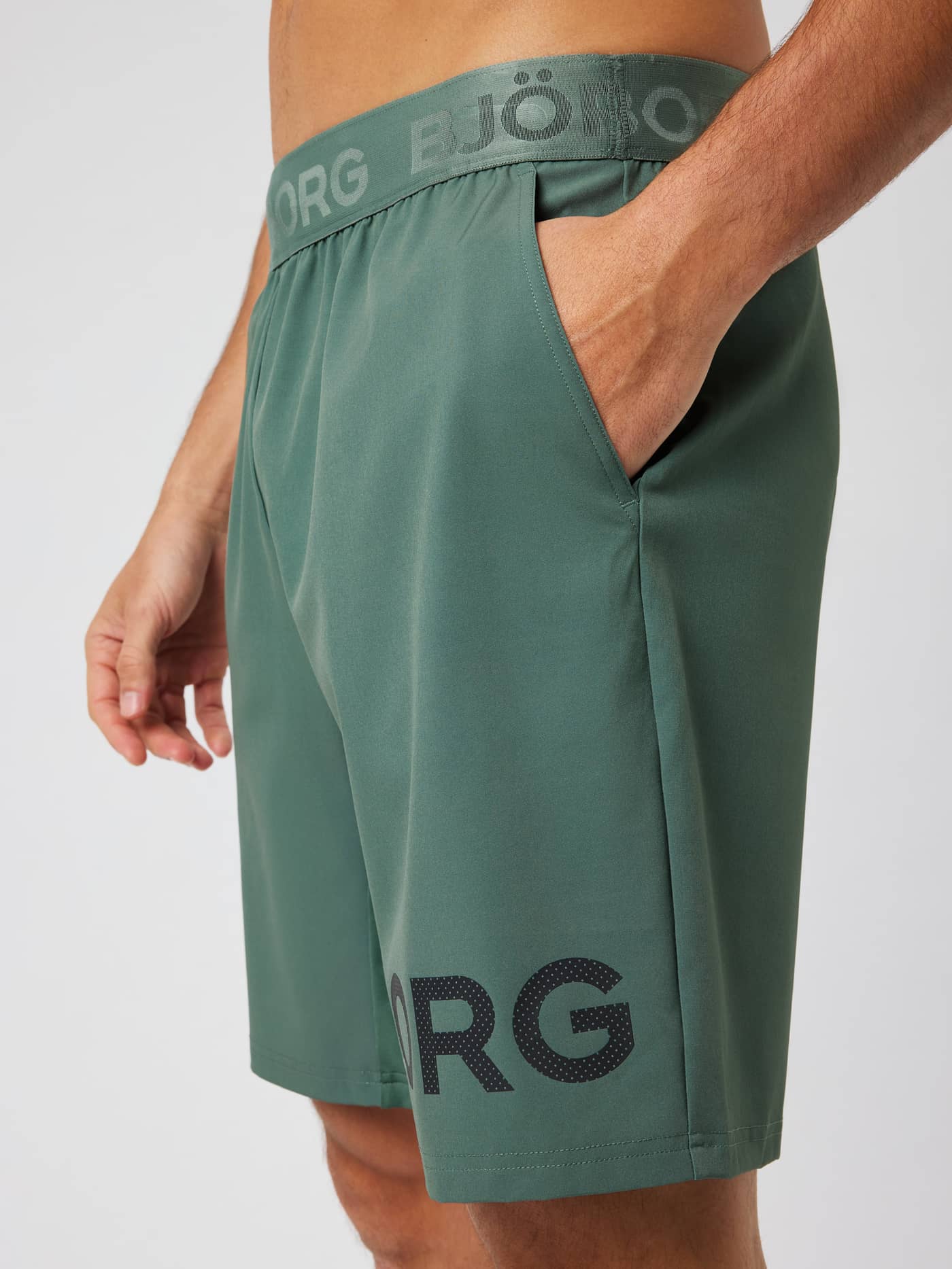 Close-up of the Borg Shorts 9 Inch in Laurel Wreath (green) highlighting the side pocket and logo waistband for training. - Image 5