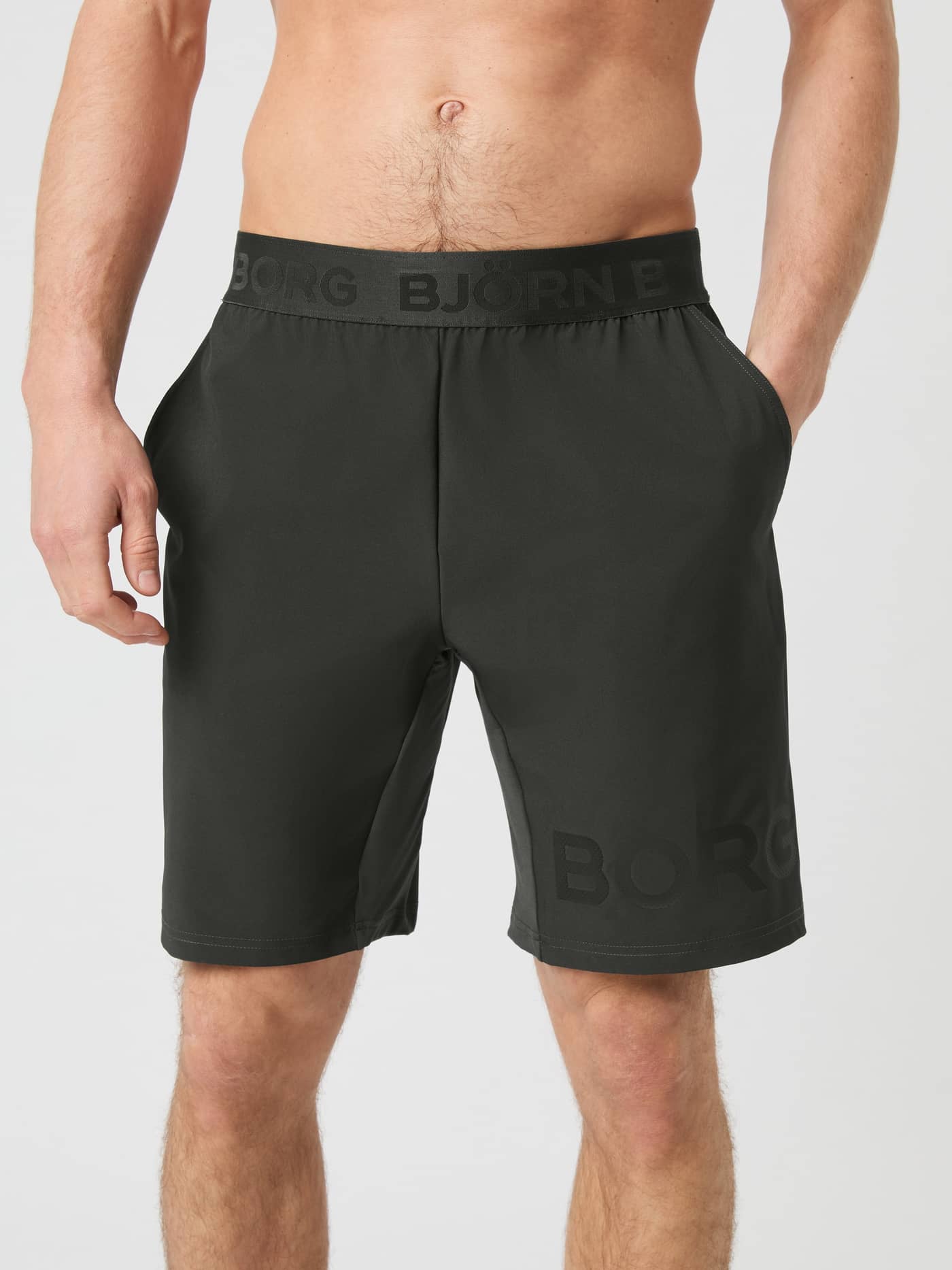 Front view of a model wearing the Björn Borg Borg 9-Inch Shorts in Peat with his hands in the pockets. - Image 1