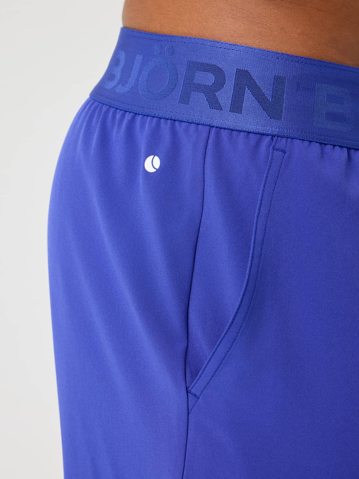 Close-up of the men's training Borg Shorts 9 Inch in Clematis Blue (Blue) with a white logo and branded blue waistband. - Image 5