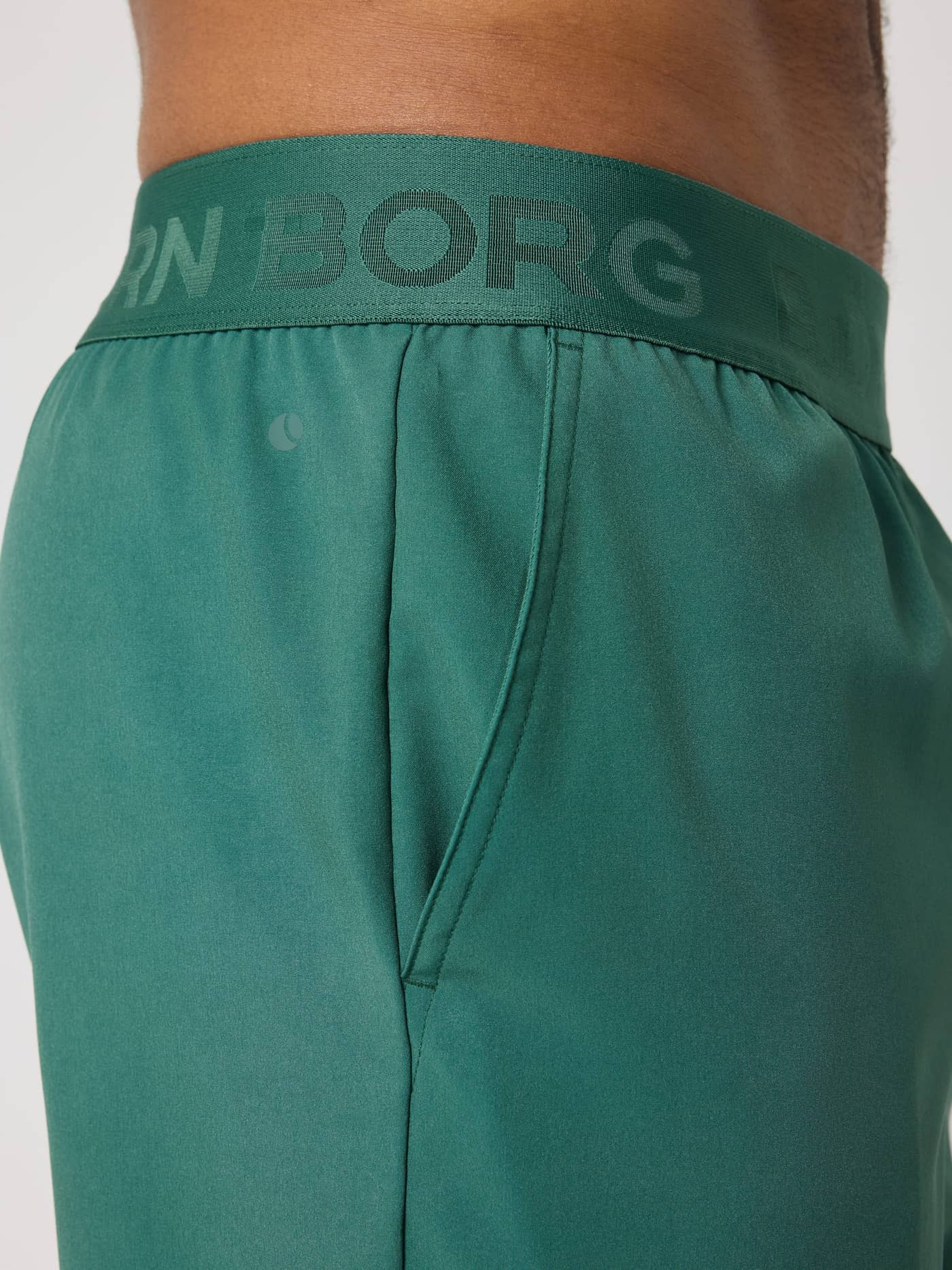 Gros plan sur le Borg Shorts 9 Inch en Mallard Green (Vert) avec logo vert et poche, idéal pour l'entraînement. - Image 4