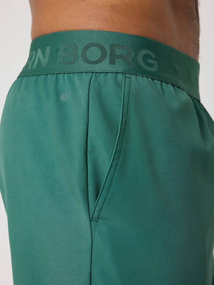 Gros plan sur le Borg Shorts 9 Inch en Mallard Green (Vert) avec logo vert et poche, idéal pour l'entraînement. - Image 4