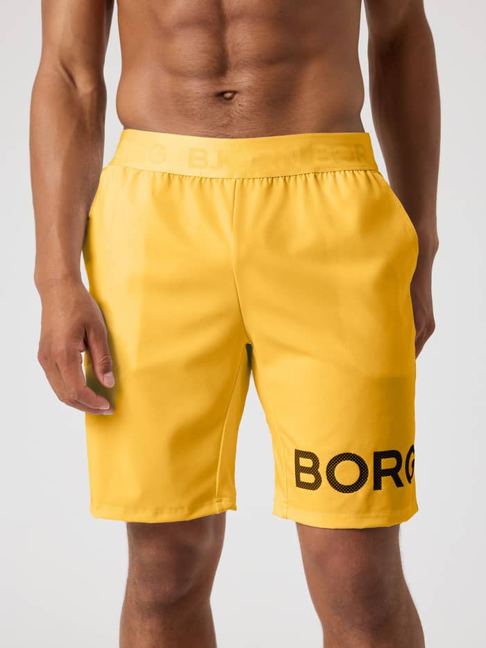 Borg Shorts 9 Inch i Citrus (Oransje) med svart perforert logo og elastisk logolinning til trening.