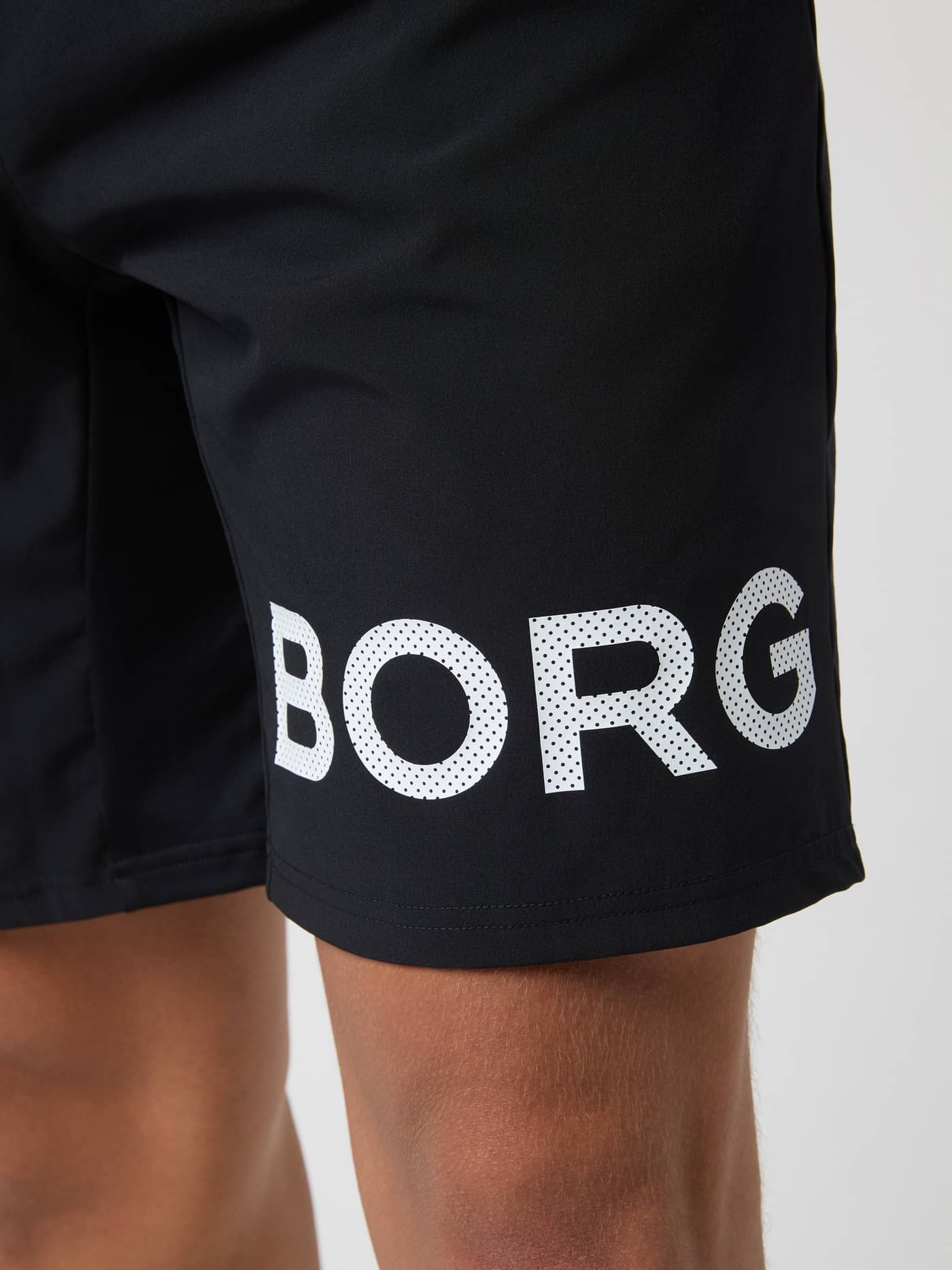 Närbild på en perforerad BORG-logotyp på benet av Borg Shorts 9 Inch i Black White Logo (Svart) för funktionell träning. - Image 6