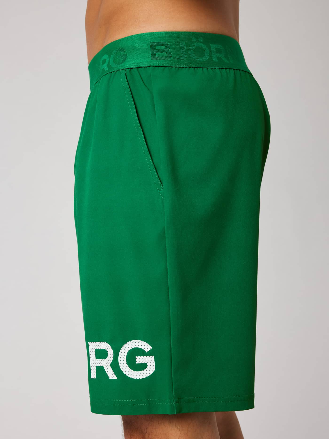 Side view of the Borg Shorts 9 Inch in Jolly Green (Green) for training, featuring side pockets and a white logo print. - Image 5