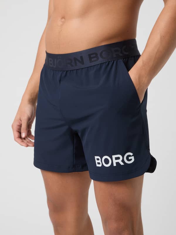 Side view of a man wearing the navy blue Björn Borg 6" Shorts, showing the branded waistband and side pocket.