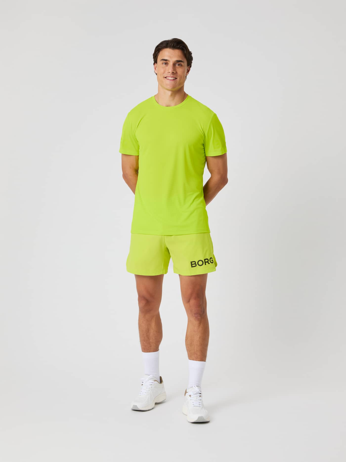 Vooraanzicht van een man in de Borg Shorts 6 Inch in Acid Lime (Groen) met zwart logo en bijpassend shirt voor training. - Image 2