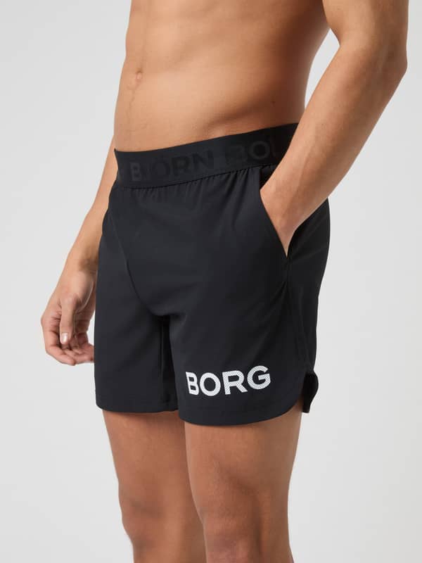 Detailed side view of a model wearing black Borg 6" Shorts, showing the side pocket and BORG logo on the thigh.
