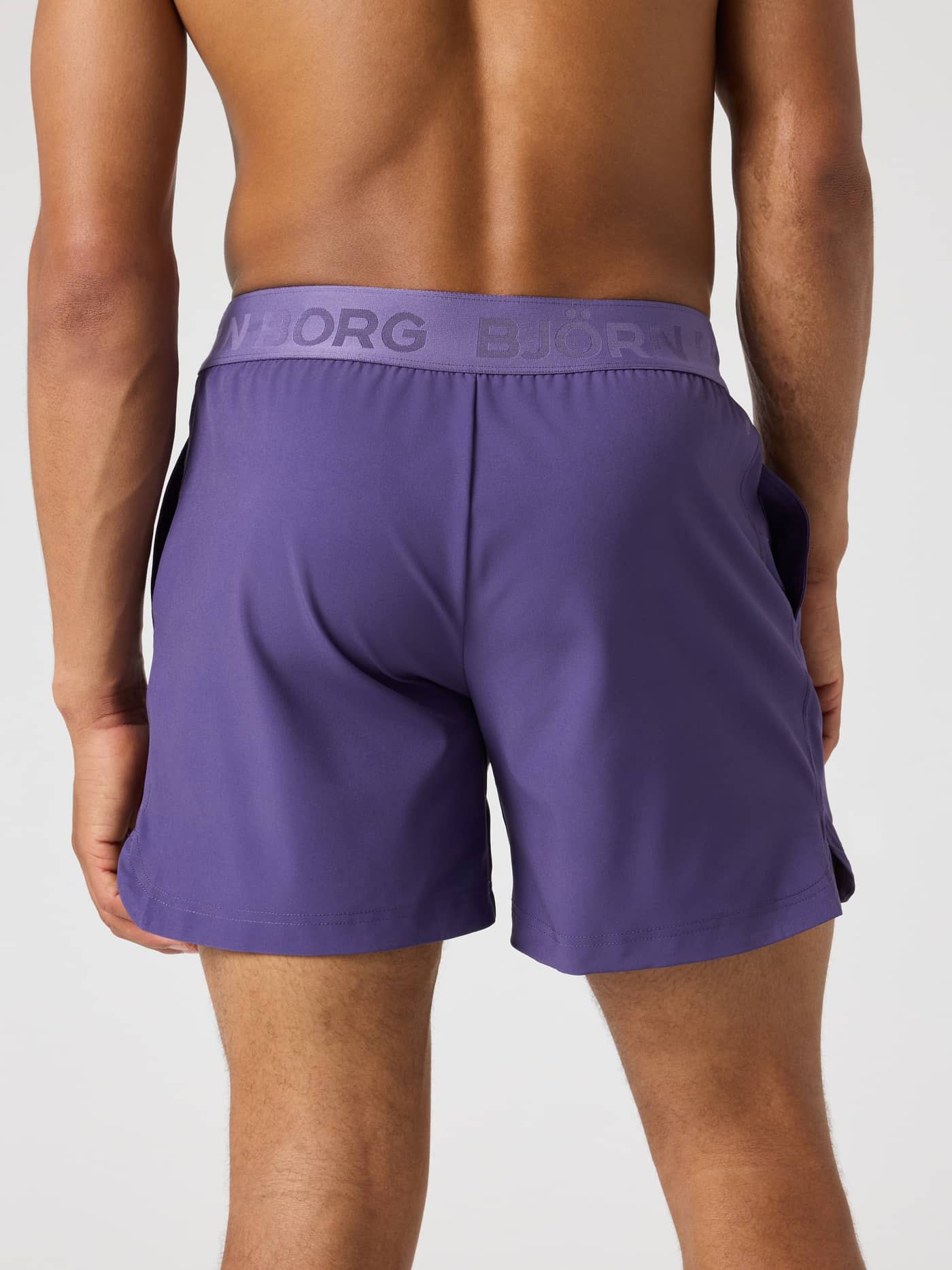Achteraanzicht van een man in de Björn Borg Shorts 6 Inch in Mystical (Paars) met paarse logotailleband voor training. - Image 2