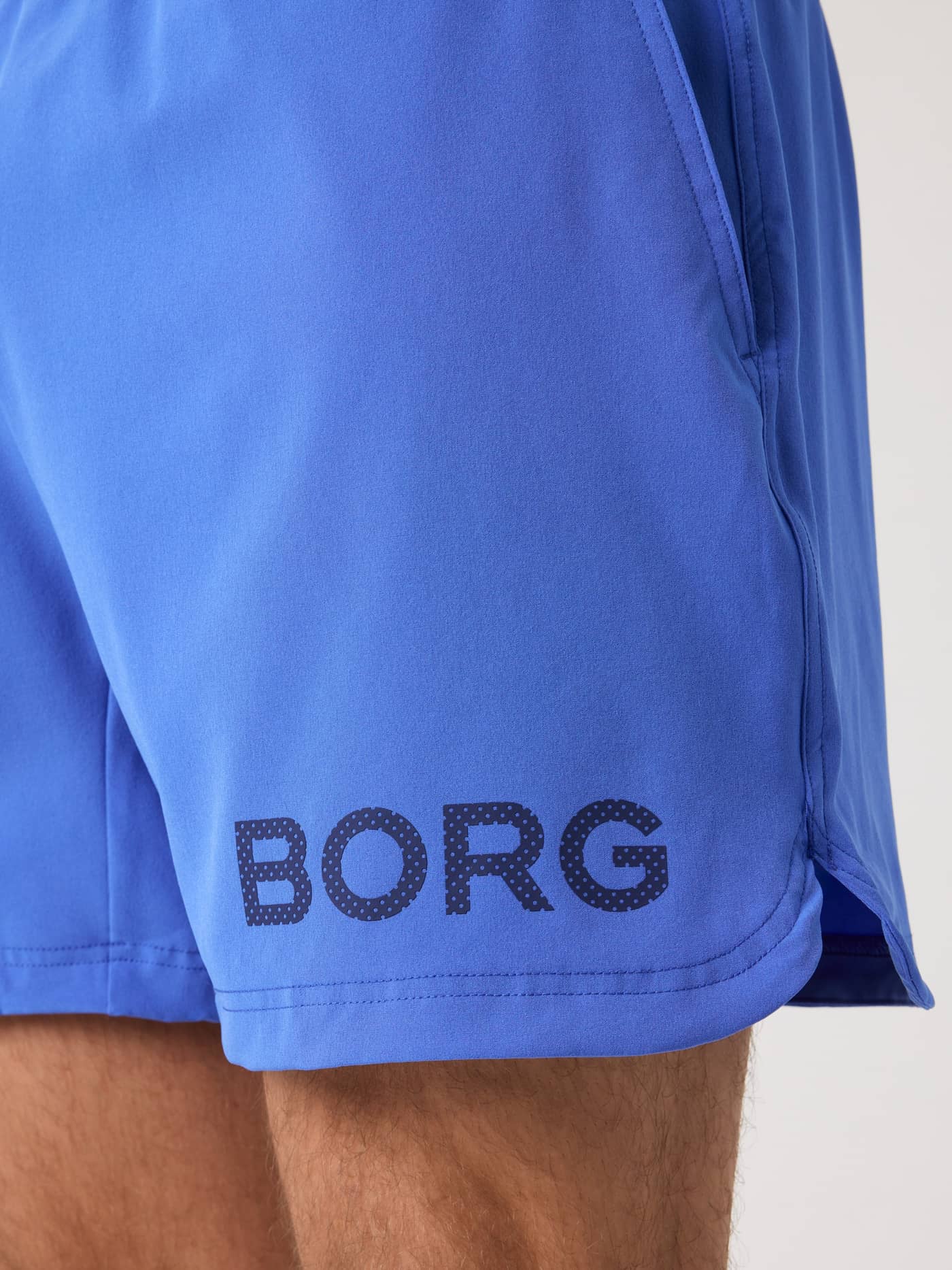 Close-up of the Borg Shorts 6 Inch in Amparo Blue (Blue) featuring a dark blue logo and side slit for training. - Image 5