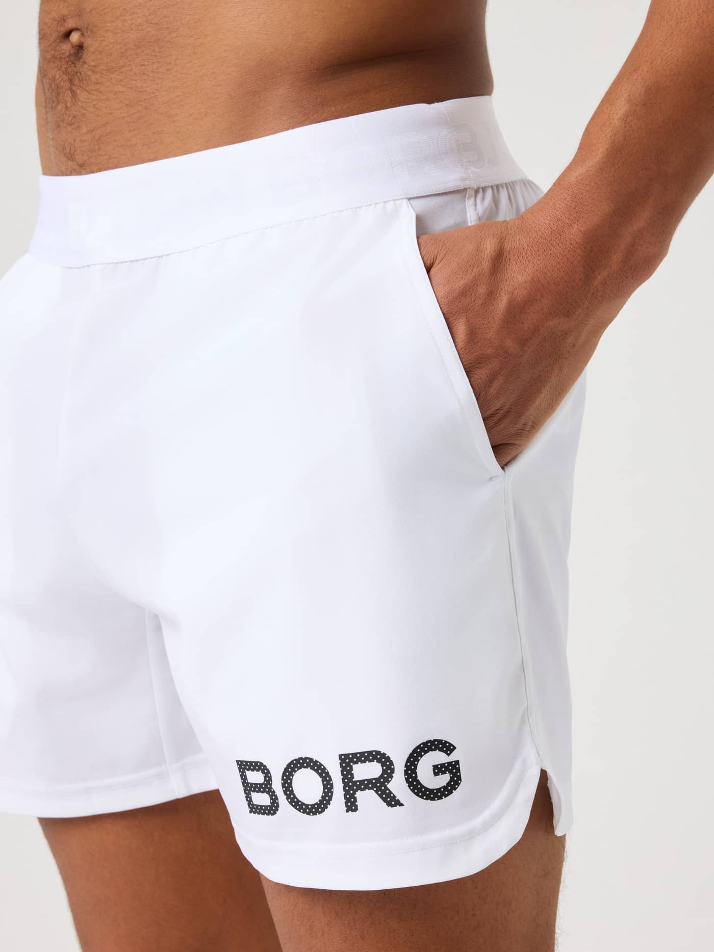 Närbild på en modell i Brilliant White (Vit) Borg Shorts 6 Inch för träning med sidoficka och svart logotyp. - Image 5