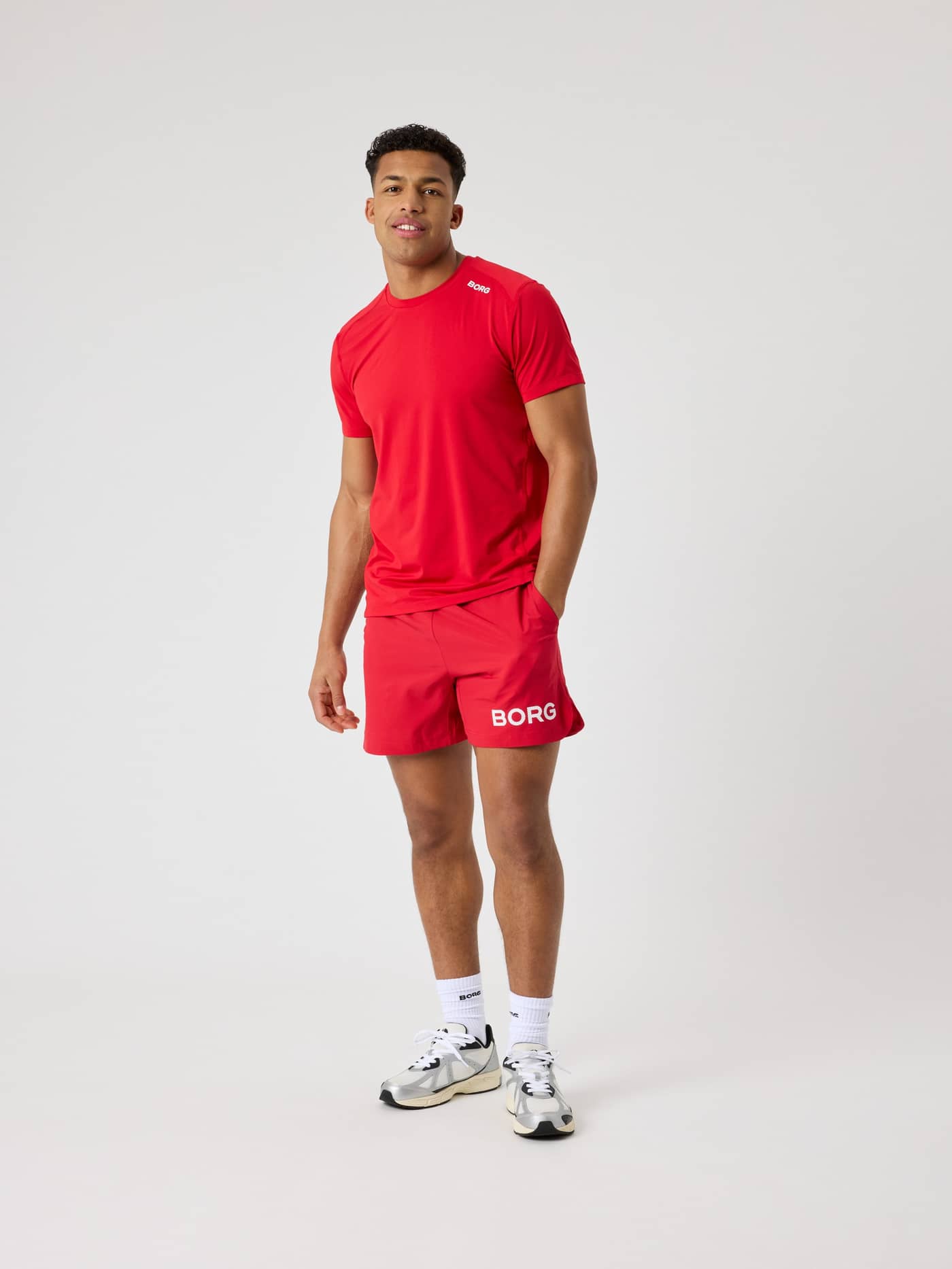 Full-body front view of a man wearing the functional Björn Borg Borg Shorts 6 Inch in Lychee (Red) for tennis training. - Image 3