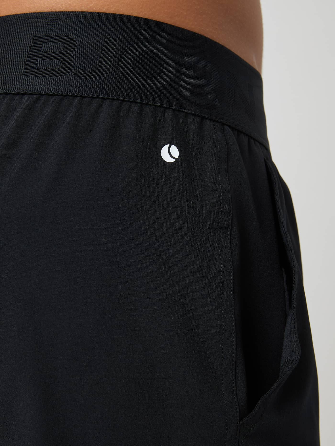 Gros plan sur le Borg Shorts 6 Inch en Black Beauty (Noir) d'entraînement avec taille élastique et petit logo blanc. - Image 4