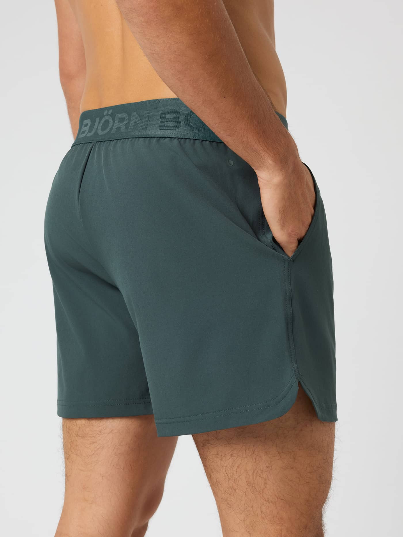 Side view of a man wearing the Borg Shorts 6 Inch in Urban Chic (Green) for technical training style. - Image 2