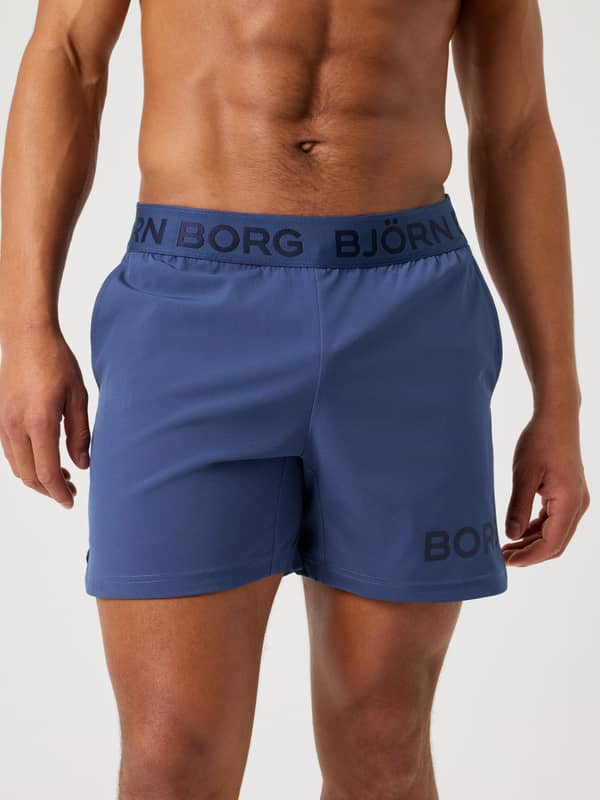 Front close-up of a model wearing the navy blue Björn Borg Borg 6" Shorts, highlighting the branded elastic waistband.