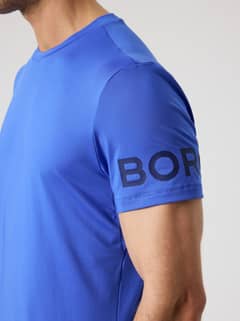 Borg T-Shirt i Amparo Blue (Blå) set fra siden med et perforeret logo på ærmet til træning. - Image 6