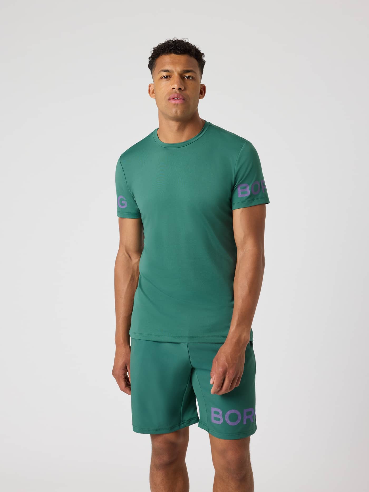 Vooraanzicht van een man in het Mallard Green (Groen) Borg T-Shirt voor training met paarse logoprints op de mouwen. - Image 1